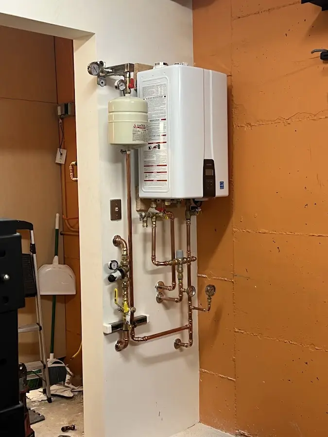 Plumbing technician inspecting water heater connections in Harvard